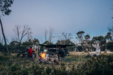 Couple relaxing at campfire in Alpine National Park Australia - CAIF24203