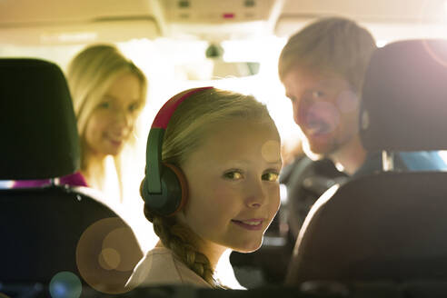 Portrait lächelndes Mädchen mit Kopfhörern auf dem Rücksitz eines Autos - CAIF24250