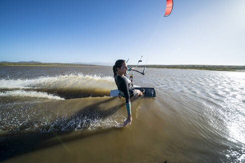 Glückliche Kiteboarderin gleitet in Mexiko mit der Hand über das Wasser - CAVF74775