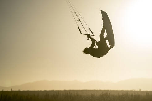 Junger männlicher Sportler beim Kiteboarden im Sonnenuntergang in La Ventana, Baja California, Mexiko - CAVF74782