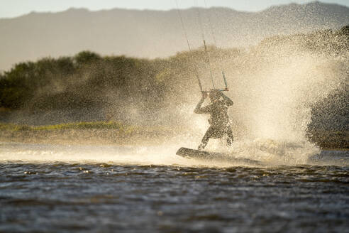 Junge Sportlerin beim Kiteboarden im Sonnenuntergang in La Ventana, Mexiko - CAVF74786