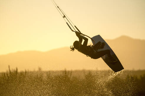 Weibliche Athletin beim Kiteboarden im Sonnenuntergang in La Ventana, Mexiko - CAVF74790