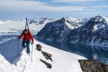 Man skinning up mountain to ski in Svalbard - CAVF74826