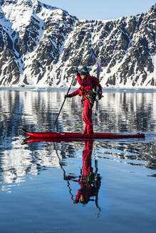 Frau paddelt auf SUP-Board mit Skiern in Jan Mayen - CAVF74827