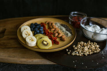 Healthy and delicious plate of fruit, nuts and seeds with yogurt and gogi berries - CAVF74861
