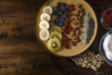 Healthy and delicious plate of fruit, nuts and seeds with yogurt and gogi berries - CAVF74863