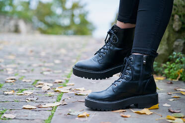 Nahaufnahme der von einer Frau getragenen Stiefel im Militärstil in Schwarz mit einem Hintergrund aus Steinboden - CAVF74952