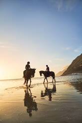 Junge Frauen beim Reiten am ruhigen Strand bei Sonnenuntergang - CAIF24284