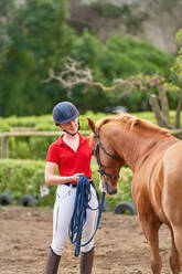 Teenager-Mädchen mit Reithelm trainiert Pferd - CAIF24299