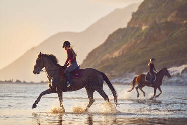 Junge Frauen beim Reiten in der Meeresbrandung - CAIF24307