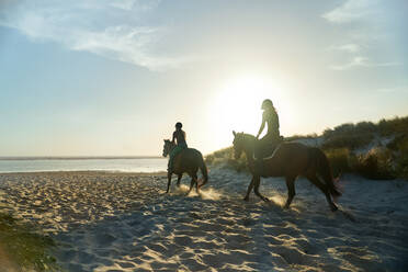 Junge Frauen reiten an einem sonnigen, idyllischen Meeresstrand - CAIF24320