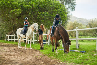 Mädchen bereiten sich auf eine Reitstunde auf einer ländlichen Pferdekoppel vor - CAIF24331
