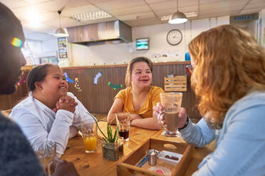 Young women with Down Syndrome talking with mentors in cafe - CAIF24353