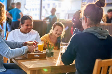 Fröhliche junge Frauen mit Down-Syndrom lachen im Cafe - CAIF24360