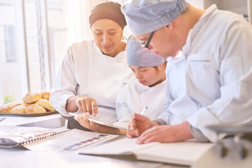 Koch und Schüler mit Down-Syndrom bei der Rezeptanalyse in der Küche - CAIF24363