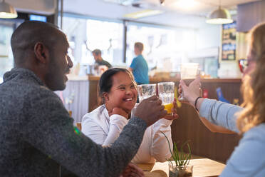 Happy young woman with Down Syndrome with friends in cafe - CAIF24372