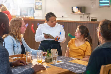 Junge Kellnerin mit Down-Syndrom nimmt in einem Café eine Bestellung auf - CAIF24386