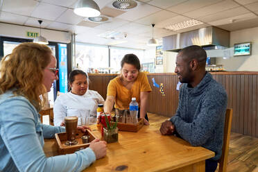 Junge Kellnerin mit Down-Syndrom serviert Getränke in einem Cafe - CAIF24395
