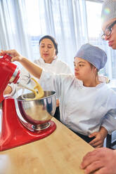 Schüler mit Down-Syndrom benutzen Standmixer im Backkurs - CAIF24405