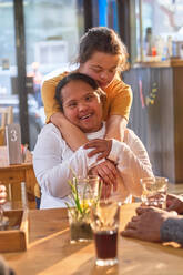 Porträt glückliche, liebevolle junge Frauen mit Down-Syndrom in einem Café - CAIF24458