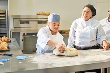 Young woman with Down Syndrome learning to bake in kitchen - CAIF24459