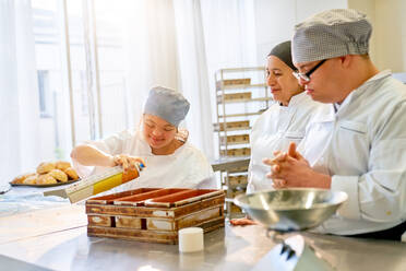 Koch und Schüler mit Down-Syndrom backen Brot in der Küche - CAIF24470