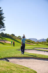 Glücklicher Mann beim Golfen, der auf einem sonnigen Golfplatz jubelt - CAIF24487