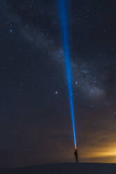 Man shining torch into sky, White Sands National Monument, New Mexico, US - ISF23794