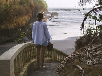 Rear view of woman walking down steps at beach - CAVF74989