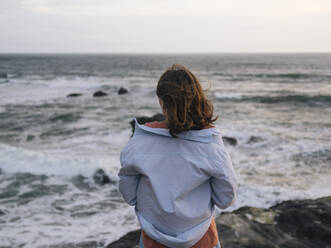 Young woman looking at ocean - CAVF74990