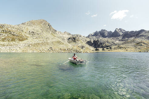 Mann in einem Ruderboot auf dem kristallklaren Suretta-See, Graubünden, Schweiz - HBIF00031