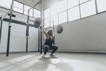 Junge Frau beim Gewichtheben im Fitnessstudio - MTBF00341