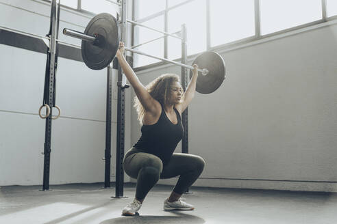 Junge Frau beim Gewichtheben im Fitnessstudio - MTBF00342