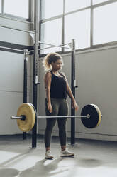Junge Frau beim Gewichtheben im Fitnessstudio - MTBF00343