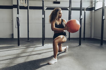 Junge Frau trainiert mit Medizinball im Fitnessstudio - MTBF00348