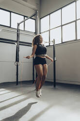 Young woman skipping rope in gym - MTBF00350