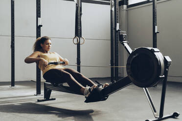 Junge Frau beim Training im Fitnessstudio mit Rudergerät - MTBF00353