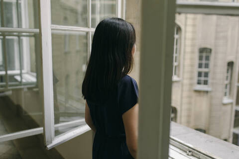 Back view of woman looking out of window stock photo