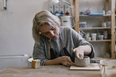 Young woman working on workpiece in pottery - JPIF00313