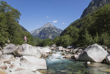 Mann steht auf einem Felsen am Fluss Verzasca, Verzascatal, Tessin, Schweiz - GWF06456