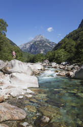 Mann steht auf einem Felsen am Fluss Verzasca, Verzascatal, Tessin, Schweiz - GWF06457
