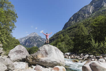 Man standing on rock at Verzasca river, Verzasca Valley, Ticino, Switzerland - GWF06458