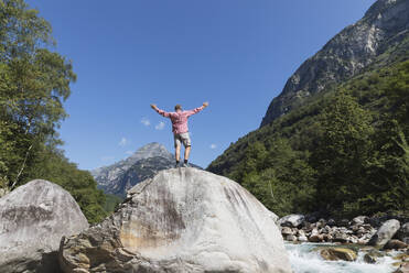 Man standing on rock at Verzasca river, Verzasca Valley, Ticino, Switzerland - GWF06459