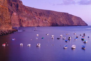 Spanien, La Gomera, Valle Gran Rey, Boote vor Küstenklippe in violetter Dämmerung vertäut - SIEF09555