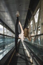 Woman ballerina stands in a tunnel lifting her leg high - CAVF75022