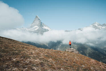 Yong Frau steht auf einem Felsen vor dem Matterhorn über den Wolken - CAVF75058