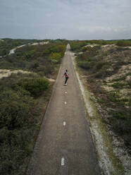 A man with long hair skating on a empty road in europe - CAVF75255