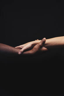 Männliche und weibliche Hände mit unterschiedlichen Hauttönen halten sich gegenseitig - CAVF75310