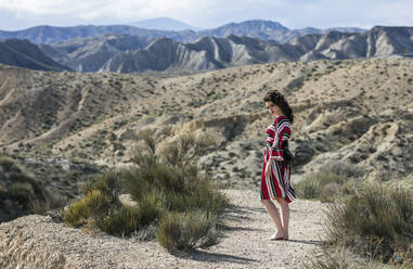 Modische Frau in gestreiftem Kleid in einer Landschaft, Almeria, Spanien - LJF01307