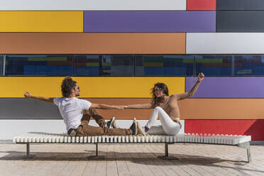 Dancers practicing on bench in front of colorful wall - DLTSF00551